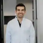 Friendly dentist or doctor in white coat in clinical setting, promoting dental health services.