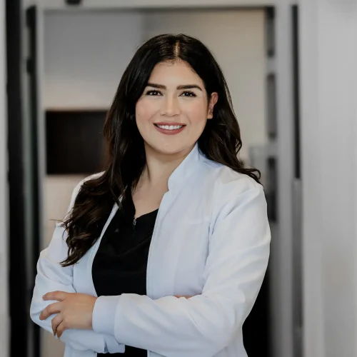 Friendly female dentist in white coat looking at camera in dental clinic.