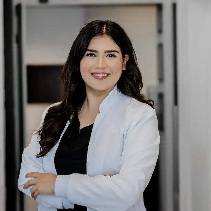 Friendly female dentist in white coat looking at camera in dental clinic.