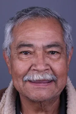 Close-up of an elderly man with a warm smile, gray hair, and a mustache, representing quality dental care.